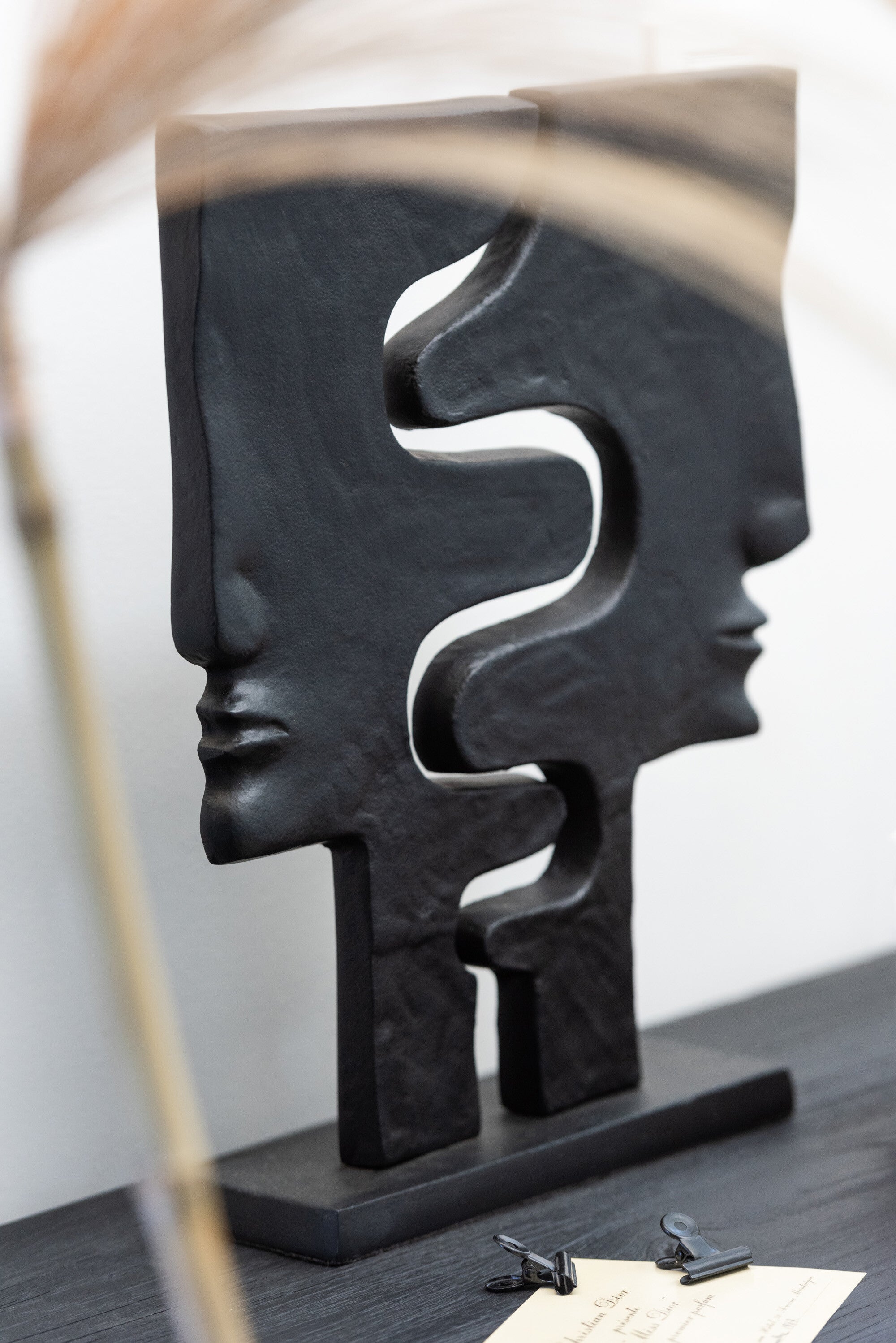 Abstract aluminum figure with two faces on a black base