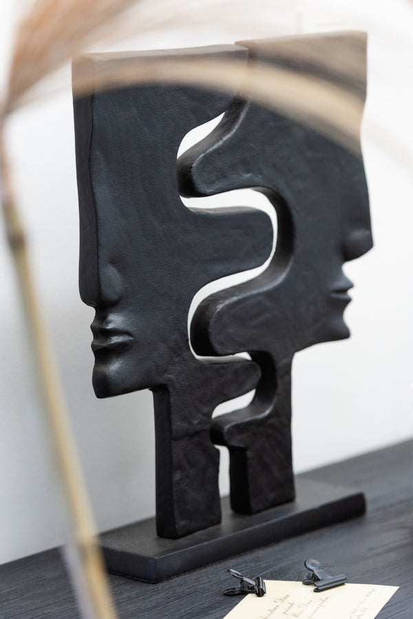 Abstract aluminum figure with two faces on a black base